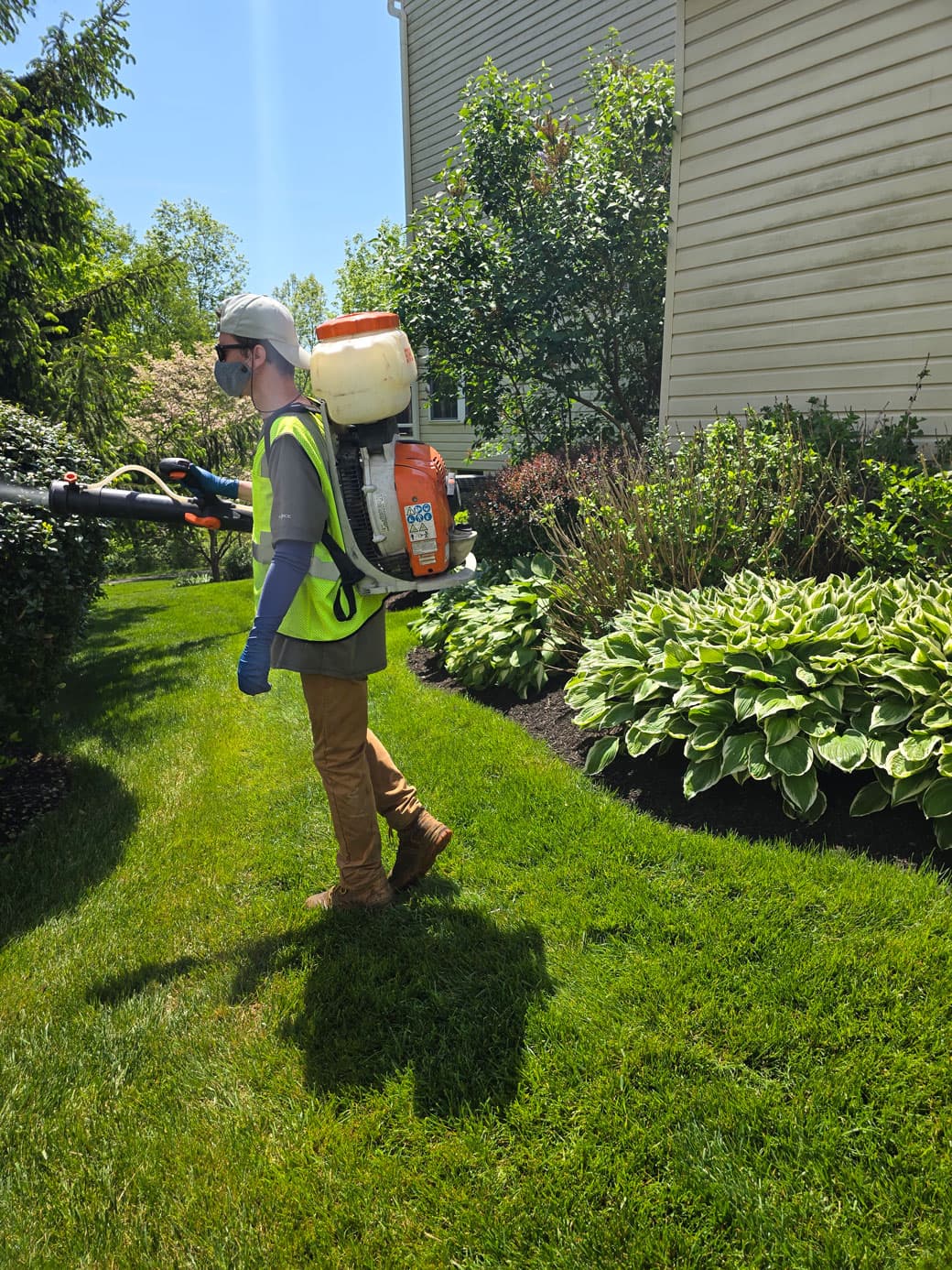 Technician applying mosquito treatment with a backpack mister